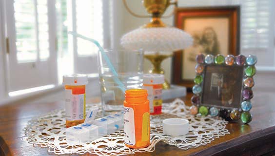 Medication bottles on a table by the bed of someone dying at home
