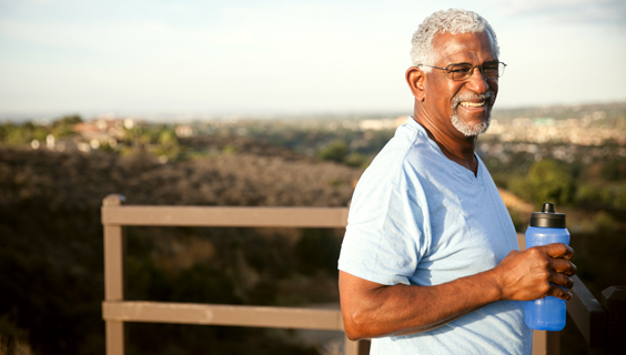 Older man drinking water in a park on a hot day