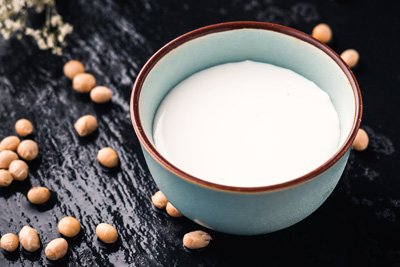 cup of soy milk with soy beans scattered around it