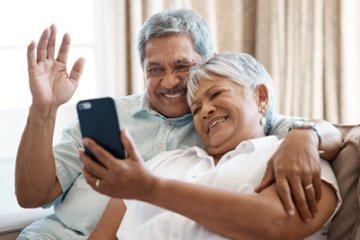 Older adult couple video chatting with family on a cell phone.