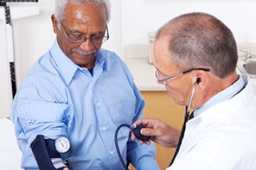Doctor checking older patient's blood pressure