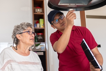 Service technician helping an older adult woman with early dementia make home repairs.