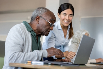 Woman helping older man at computer