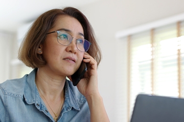 Asian woman makes a call while on her laptop