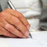 Older person's hand writing down health care directives