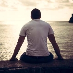 Man sitting with his back to the camera at the beach