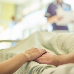 2 people holding hands on a hospital bed