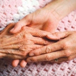 2 people holding hands on a pink blanket