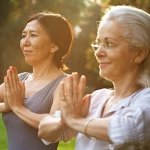 2 older women doing yoga meditation