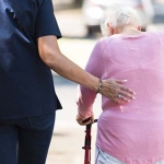 Professional caregiver helping an older woman using a walker