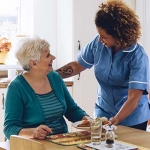 Older woman and her caregiver giving her a meal