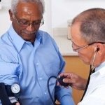 older man getting blood pressure checked by doctor