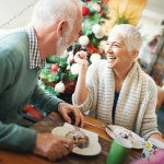 An older man and woman looking at each while eating breakfast during the holidays
