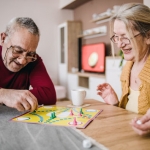 Older adult with Alzheimer's playing a board game with a friend