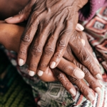 close-up of hands of older adult being held by hands of younger adult