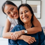 Mother and daughter smiling and hugging. 