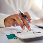 hand holding pen and clicking buttons on calculator