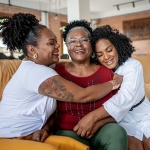 Two young women hug their older mother