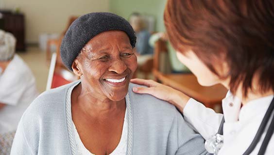 Older woman in a nursing home with a care provider's hand on her shoulder